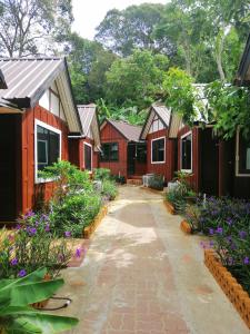 a row of red houses with flowers and trees at Phi Phi Long Beach Bungalow ( Had Yao) in Phi Phi Islands