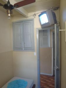 Habitación con ventilador de techo y TV en la pared. en Hospedagem Ledo en Río de Janeiro