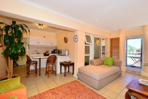 a living room with a couch and a kitchen at Secret Garden Guesthouse in Bloubergstrand