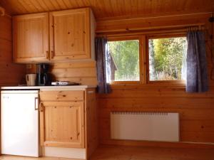 4 persoons Stuga في Hammarstrand: مطبخ مع دواليب خشبية ونافذة