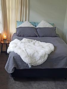 a white blanket on a bed in a bedroom at Central Rotorua Beauty in Rotorua