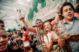 un grupo de personas animando en un bar con cerveza en ESN Oktoberfest Campsite en Múnich