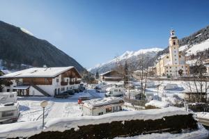 ein schneebedecktes Dorf mit einer Kirche in der Unterkunft Aparthaus Camping Stubai in Neustift im Stubaital