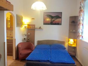 a bedroom with a blue bed and a chair at Chalupa U Potoka in Josefŭv Dŭl
