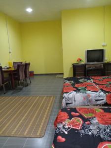 a room with two beds and a tv and a table at Hotel Murah Pasir Puteh in Pasir Puteh
