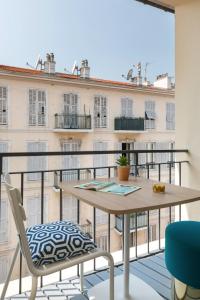 un tavolo e sedie su un balcone con un edificio di The Deck Hotel by Happyculture a Nizza