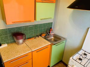 ナディムにあるапартаменты на полярной 14の小さなキッチン(オレンジと緑のキャビネット、シンク付)