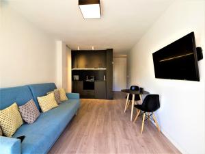 a living room with a blue couch and a kitchen at Rambla Suite Estudio in Alicante