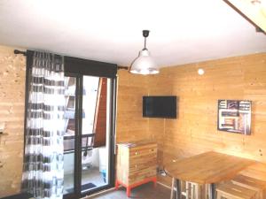 um quarto com uma parede de madeira com uma mesa e uma televisão em L'esprit chalet by SODA em Luchon