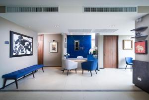 een wachtkamer met een blauwe bank en een tafel bij Amp Am House Bangkok Hotel in Bangkok