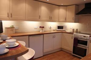 a kitchen with white cabinets and a wooden counter top at Silhouette Cottage in Coleford