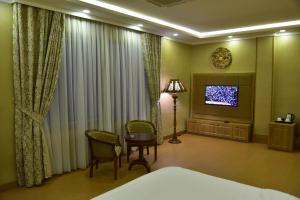 スライマーニーヤにあるParezh Hotelのベッド、テーブル、テレビが備わるホテルルームです。