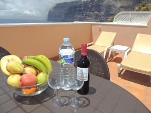 a table with two bottles of wine and a bowl of fruit at Romantic Retreat with Marine View in Acantilado de los Gigantes