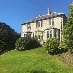 una casa vieja en una colina con césped verde en Braeside en Alnwick