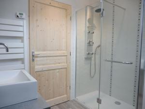 y baño con ducha, lavabo y puerta de ducha. en Le petit Kichon en Gérardmer