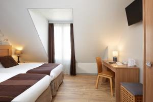 パリにあるオテル アラーヌのベッドとデスクが備わるホテルルームです。