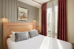 1 dormitorio con cama blanca y ventana en Hôtel Alane en París