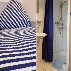 a bedroom with a blue and white striped pillow and a bathroom at Hotel Garni in Herborn