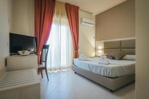 a bedroom with a bed and a desk and a television at Hotel Costa Azul in Balestrate