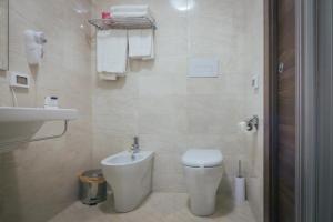 a white bathroom with a toilet and a sink at Hotel Costa Azul in Balestrate