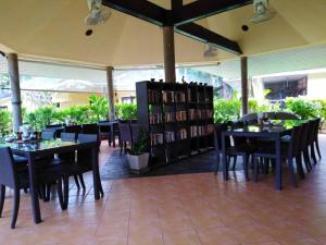 a restaurant with tables and chairs and a book shelf at Palm Garden Resort in Khao Lak