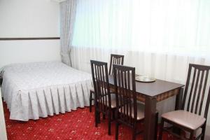 a room with a bed, table and chairs at Lazurny Bereg Hotel in Tyumen