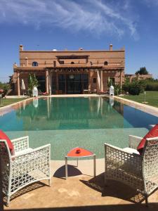 duży basen z dwoma krzesłami i budynek w obiekcie Villas Fleurs Marrakech w Marakeszu