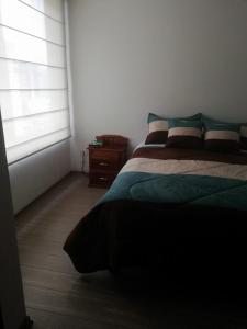 Un dormitorio con una cama verde y una ventana. en Suite M&M, en Quito