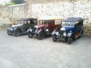 three old cars parked next to a stone wall at Contact Hôtel du Cerf in Château-Gontier