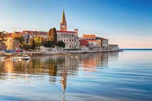 a city on the water with a church in the distance at Apartments Villa Anton in Poreč