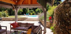 a patio with a couch under a pergola next to a pool at La Tour Charlemagne in Château-Chalon