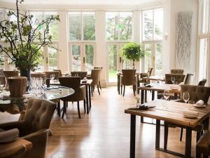 a restaurant with tables and chairs and windows at Forest Side Hotel in Grasmere