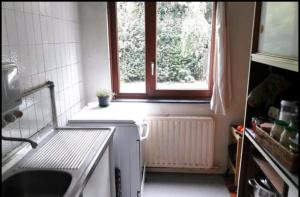 una piccola cucina con finestra e lavandino di Chez Mimi - chambre vue parc a Bruxelles
