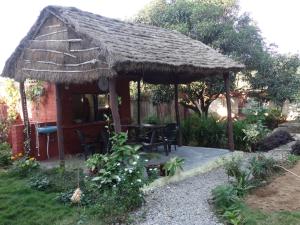a hut with a table and chairs in a garden at Champions Bungalow in Rāmnagar