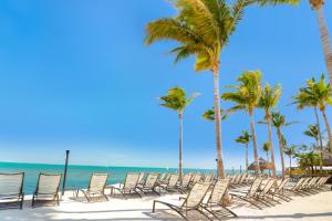 Fiesta Key RV Resort Premium Room 3 في لايتون: صف من الكراسي على شاطئ به نخيل
