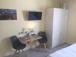1 dormitorio con 2 sillas y mesa con TV en Haus Solymar App. 59, en Grömitz