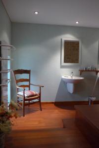 a bathroom with a chair and a sink at Le Lavoir de Meziat in Vinzelles