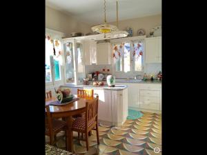 a kitchen with white cabinets and a table and chairs at Pangiotas Pencione in Karpathos +19 photos