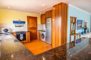 a kitchen with wooden cabinets and a stainless steel refrigerator at Happy Waves Holiday Home in Jeffreys Bay
