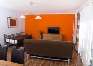 ラー・アン・デア・ターヤーにあるAppartementhaus Thermeneckのオレンジ色のリビングルーム(ソファ、テレビ付)