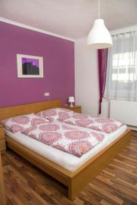 1 dormitorio con 1 cama con pared morada en Appartementhaus Thermeneck en Laa an der Thaya