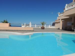 a large blue swimming pool in front of a house at Magical Apt. with Sea View & Cliff in Acantilado de los Gigantes