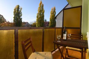 stół z 2 krzesłami i butelkę wina na balkonie w obiekcie Vitalis Apartman w Egerze
