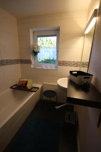 un bagno con vasca, lavandino e finestra di Ferienhaus an der Iller a Aitrach