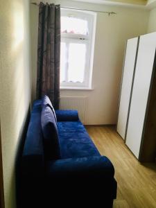 un divano blu in una stanza con finestra di Ferienwohnung für Alt und Jung a Sonneberg