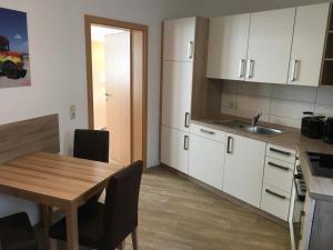 a kitchen with white cabinets and a wooden table with a sink at Ferienwohnung für Alt und Jung in Sonneberg