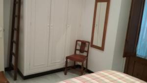 1 dormitorio con silla, espejo y cama en Calle Herbolarios, en Sevilla
