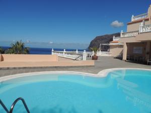 a swimming pool in front of a house with the ocean at Luxury Apt. with Stunning Sea View in Acantilado de los Gigantes