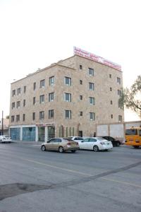 een groot bakstenen gebouw met auto's geparkeerd op een parkeerplaats bij MY HOTEL Nizwa Residence Hotel Apartement نزوى ريزيدنس in Nizwa