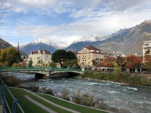 un ponte su un fiume con montagne sullo sfondo di Casa di vivian in montagna con giardino Alpe di siusi Fie allo sciliar Bolzano a Fié allo Sciliar